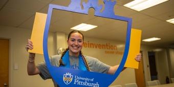 Student posing with the Pitt shield